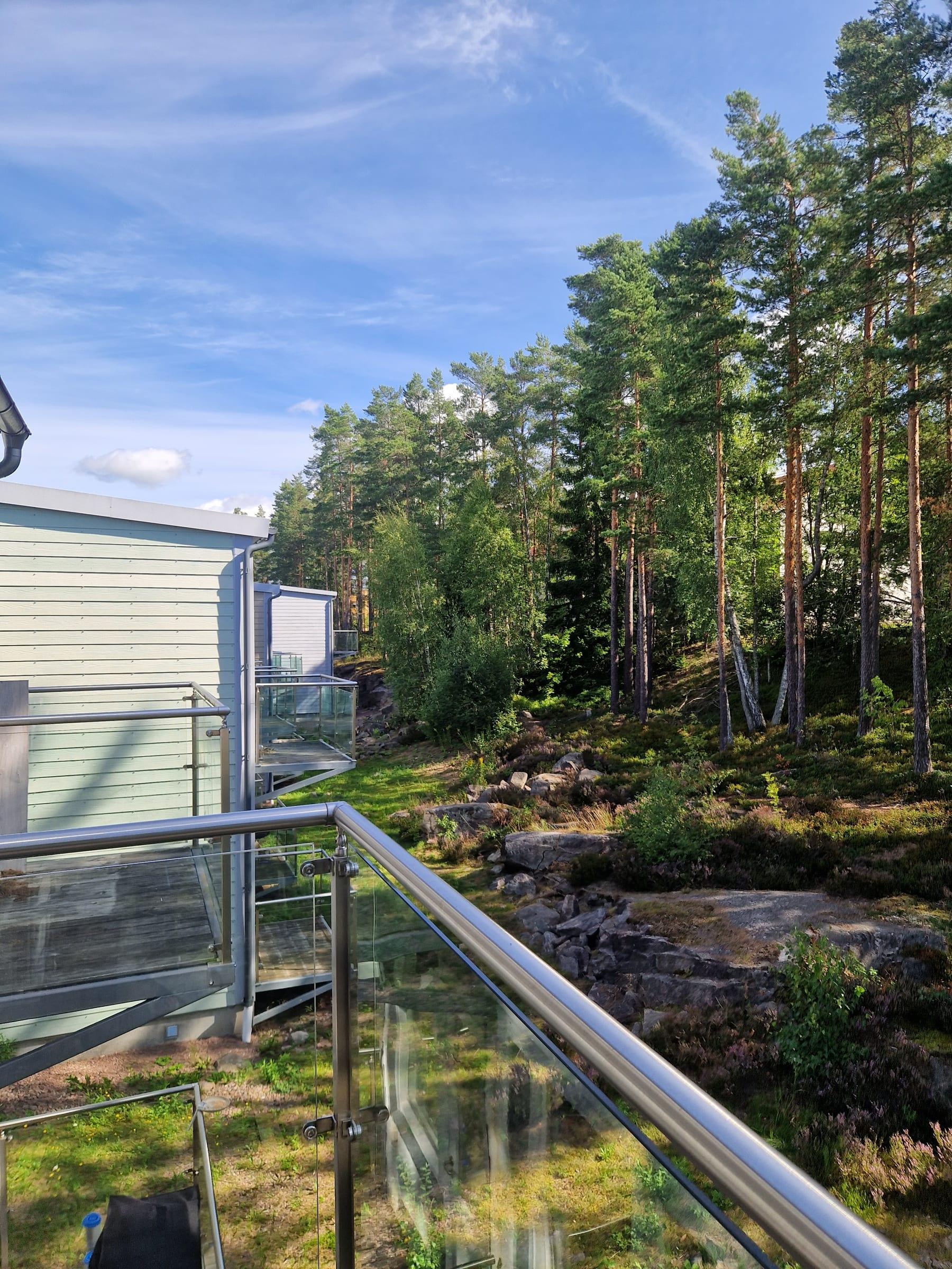 Utsikt från balkongen mot tallskogen och berghällarna intill husen